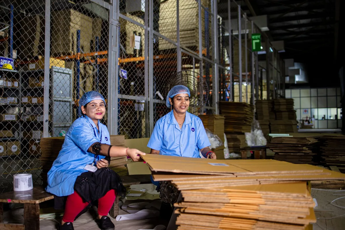 Dua anggota crew warehouse mengemas kardus pesanan di gudang ecommerce