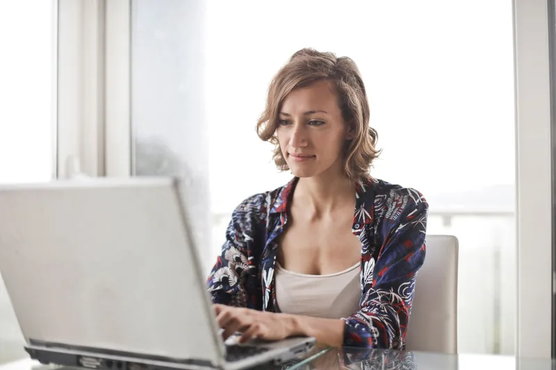 A woman typing on a laptop in a bright, modern home office setting