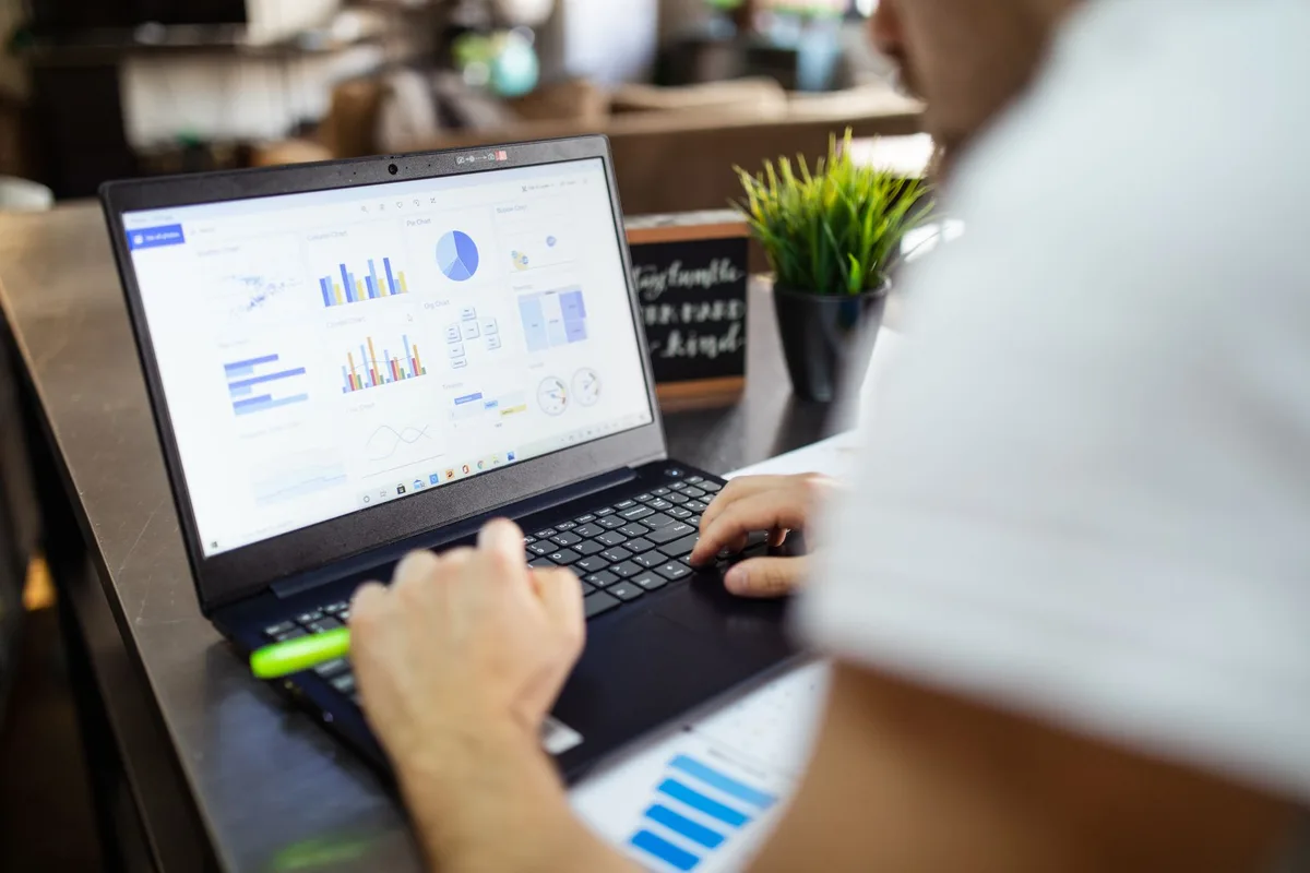 Laptop displaying spreadsheet charts and data tables in a modern office