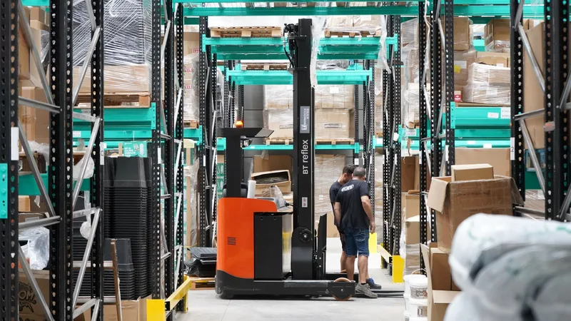 Warehouse aisle with shelving and a forklift moving inventory
