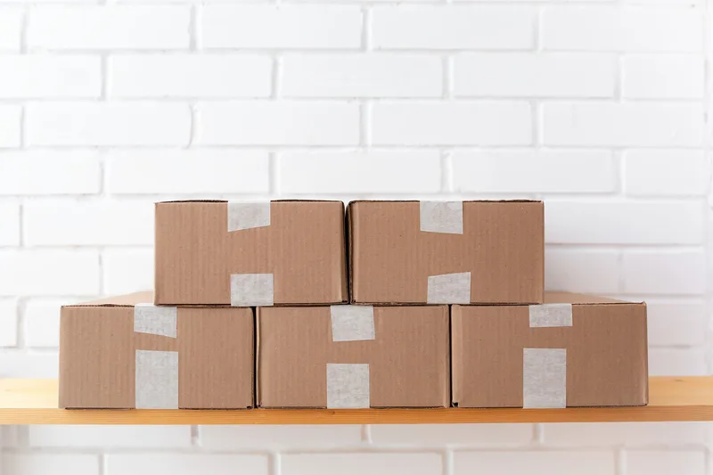 Ecommerce seller processing orders on a laptop with parcels ready for dispatch, the manual workflow an OMS replaces with a centralised queue