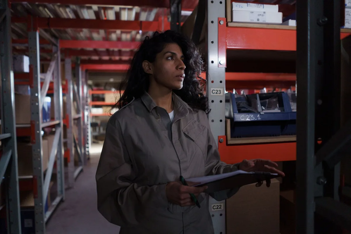 Warehouse worker checking inventory stock levels in a storage facility, the kind of stock check order procurement software automates