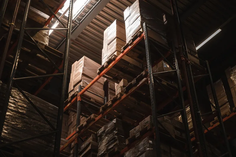 Warehouse shelves stocked with cardboard boxes, the kind of inventory a procurement system tracks across multiple marketplace listings
