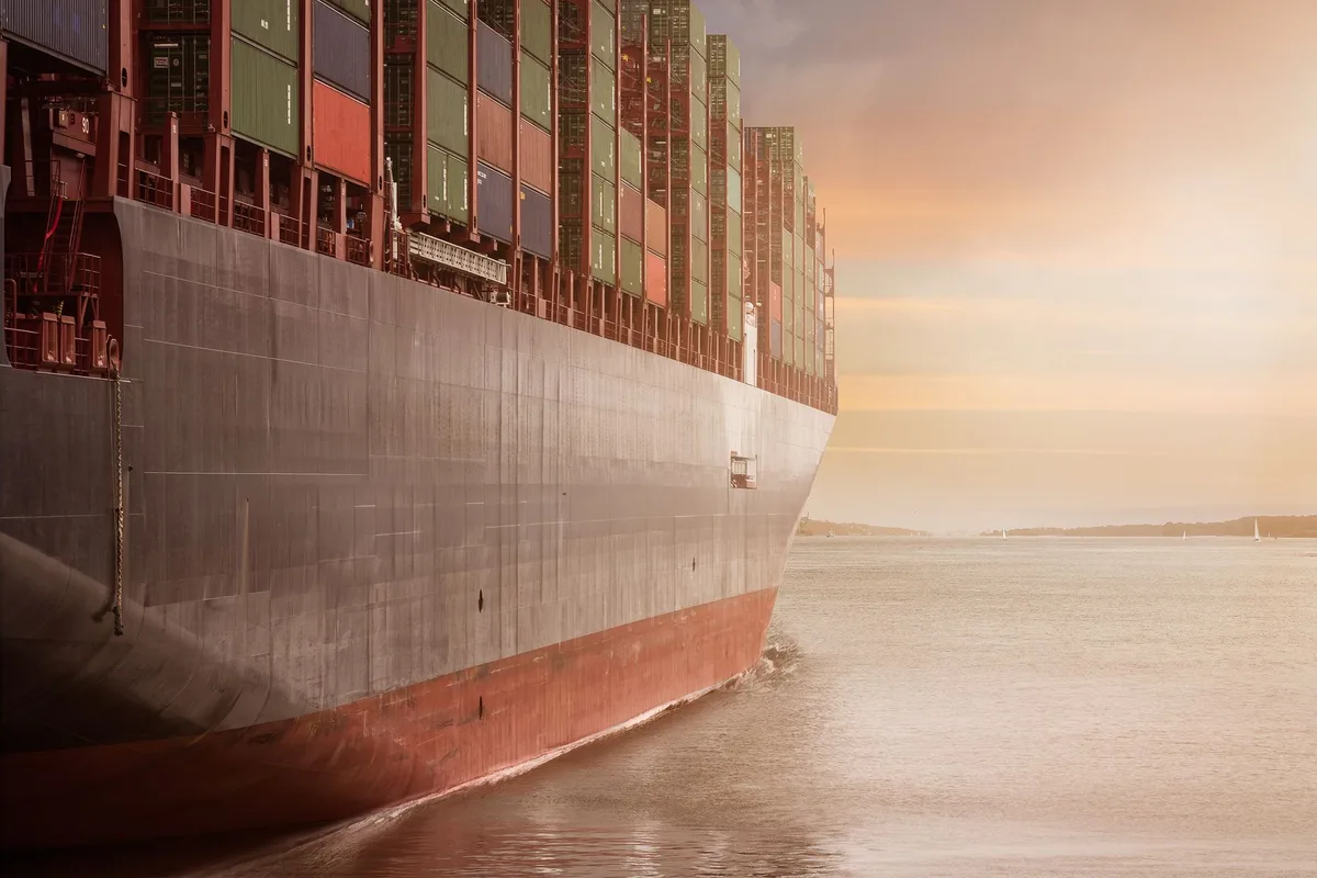 Cargo ship loaded with shipping containers crossing open water, representing a cross-border supplier order bound for an Indonesian ecommerce warehouse