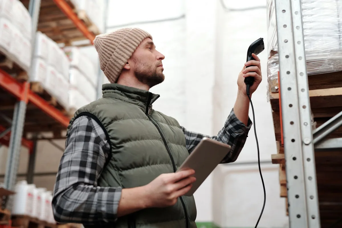Staf gudang menggunakan scanner barcode dan tablet untuk mengelola inventory dengan warehouse system management software di gudang ecommerce Indonesia