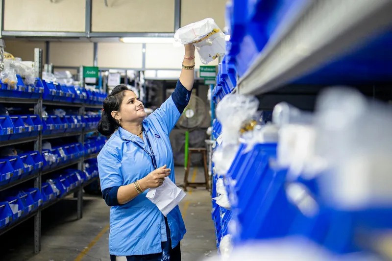 Female warehouse worker organizing inventory on industrial shelving, representing systematic warehouse setup for ecommerce operations