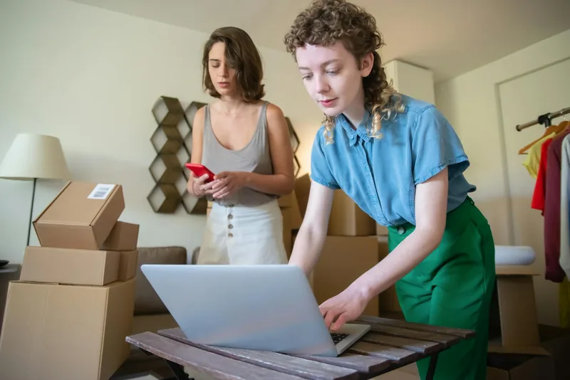 Ecommerce seller managing orders on a laptop with inventory in the background